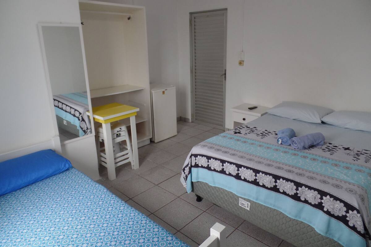 Une chambre avec un lit, un bureau, une armoire et un petit réfrigérateur.