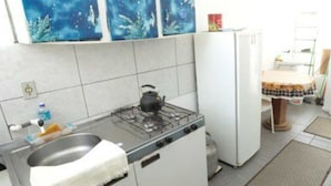 Cocina compacta con estufa a gas, lavamanos y refrigerador.