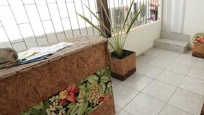 Un balcón con suelo de baldosas, un banco de madera con tapicería floral y plantas en macetas.