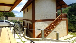A two-story building with a staircase leading to the upper floor, a covered porch area, and a car parked outside. - Pousada Vista da Serra (Camanducaia)