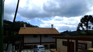 A two-story house with a tiled roof, a car parked in the driveway, and a satellite dish on the roof. - Pousada Vista da Serra (Camanducaia)