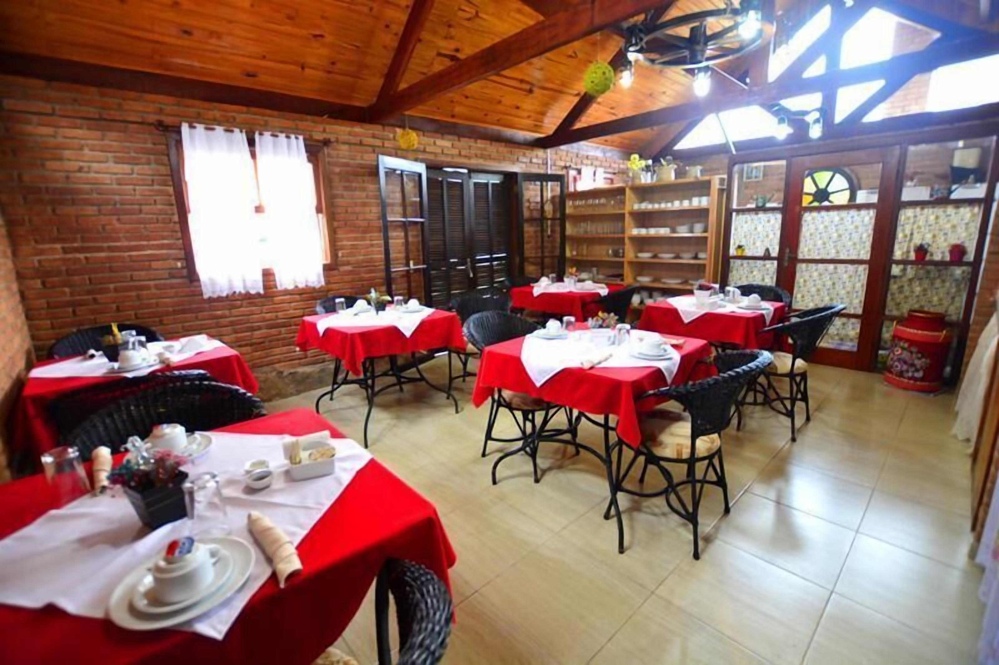 Un restaurante con manteles rojos, sillas de mimbre y paredes interiores de ladrillo.