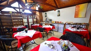 A dining area with tables set for meals, a kitchen area, and a rustic wooden ceiling. - Pousada Aconchego (Camanducaia)