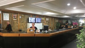 A hotel reception area with a reception desk, multiple monitors, and framed pictures on the wall. - Hotel Grão Pará (Belém)