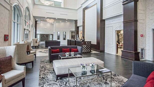 A spacious lobby with high ceilings, a grand staircase, and a gift shop. - The Delavan Hotel & Spa (Bowmansville)