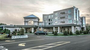 A multi-story hotel with a stone facade, a prominent entrance with a metal archway, and a parking lot in front. - The Delavan Hotel & Spa (Bowmansville)