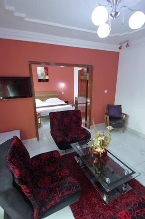 A modern living room with a sofa set, a coffee table, and a TV mounted on the wall. - Hôtel Résidence La Corniche (Dakar)