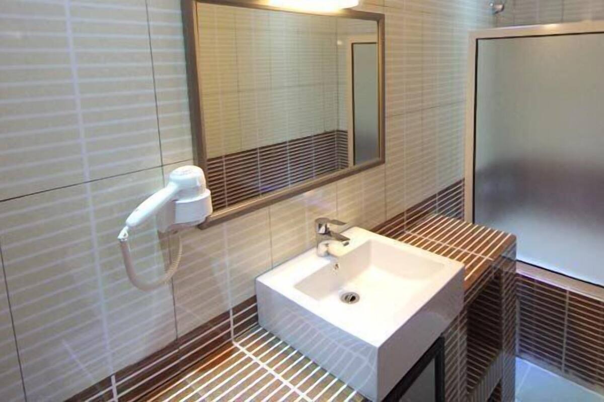Un baño moderno con lavamanos blanco, un espejo y zona de ducha.
