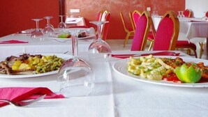 Uma mesa de jantar com pratos de comida, copos de vinho e talheres.