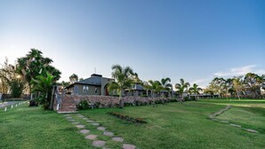 A residential property with a stone pathway leading to a house with a stone facade and a red roof. - Pousada Camelot (Alto Paraíso de Goiás)