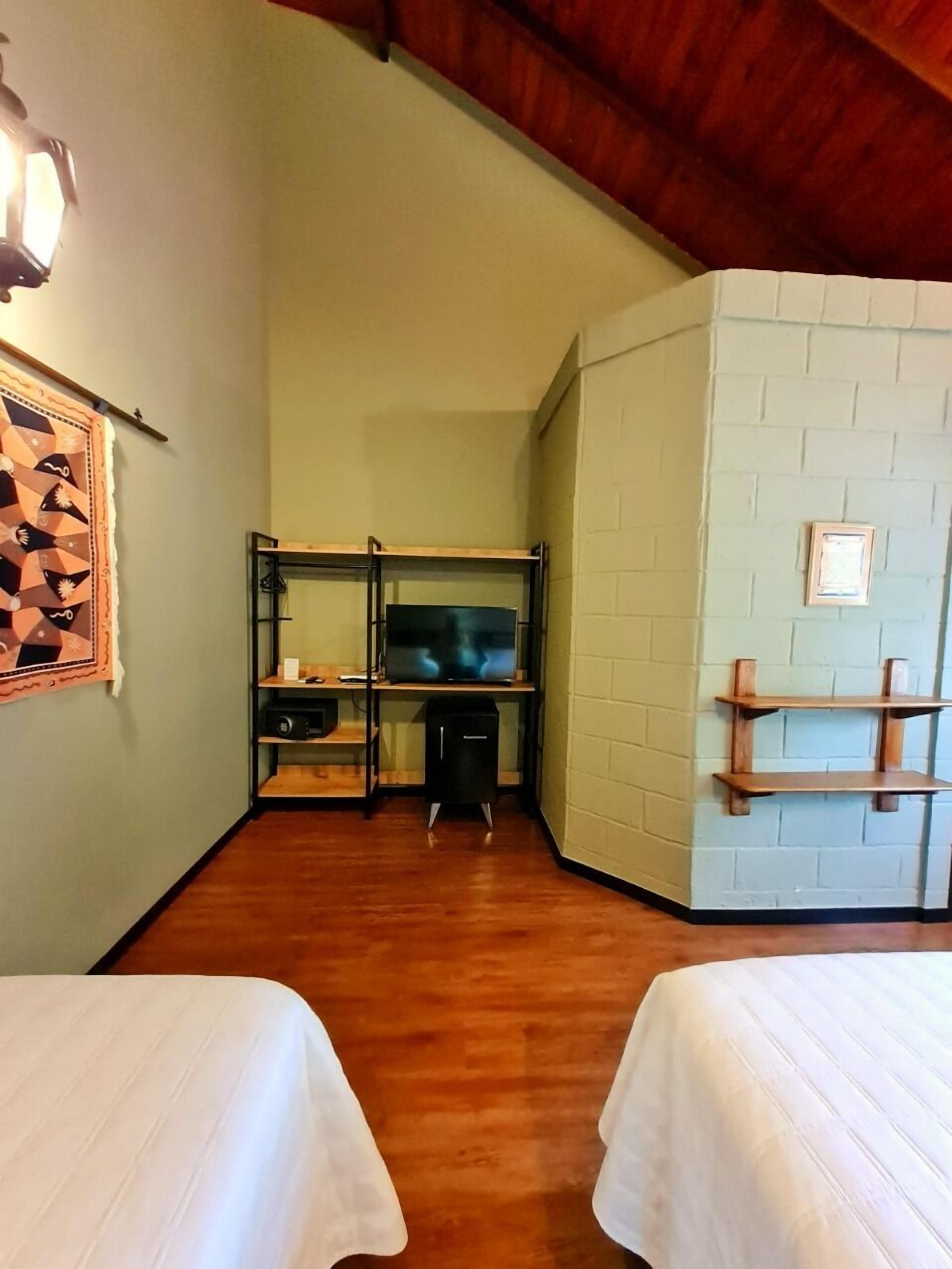 A room with two beds, a TV on a shelf, and a small cabinet.