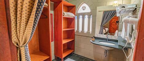 A bathroom with a wooden shelf unit, a sink with a mirror, and a towel rack.