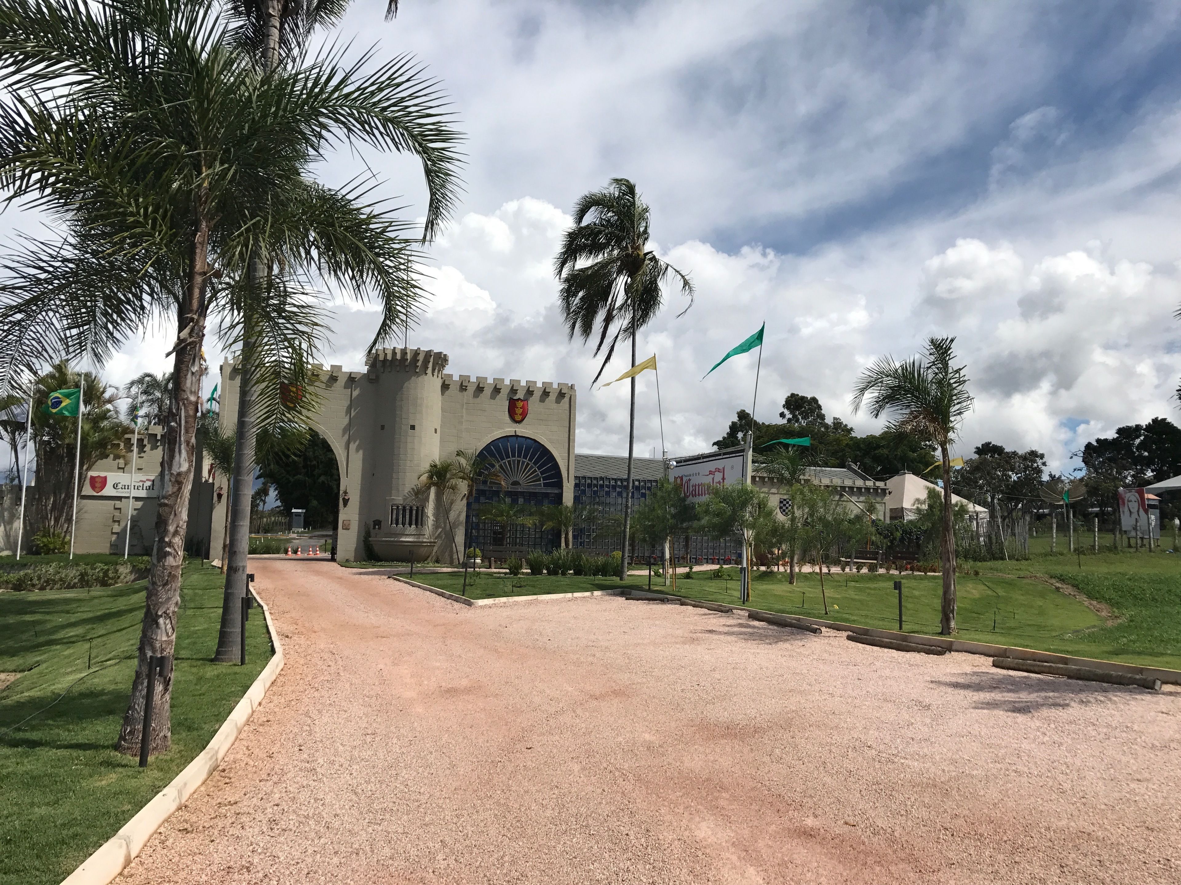 Un edificio al estilo de castillo con una gran entrada en arco, palmeras y varias banderas.