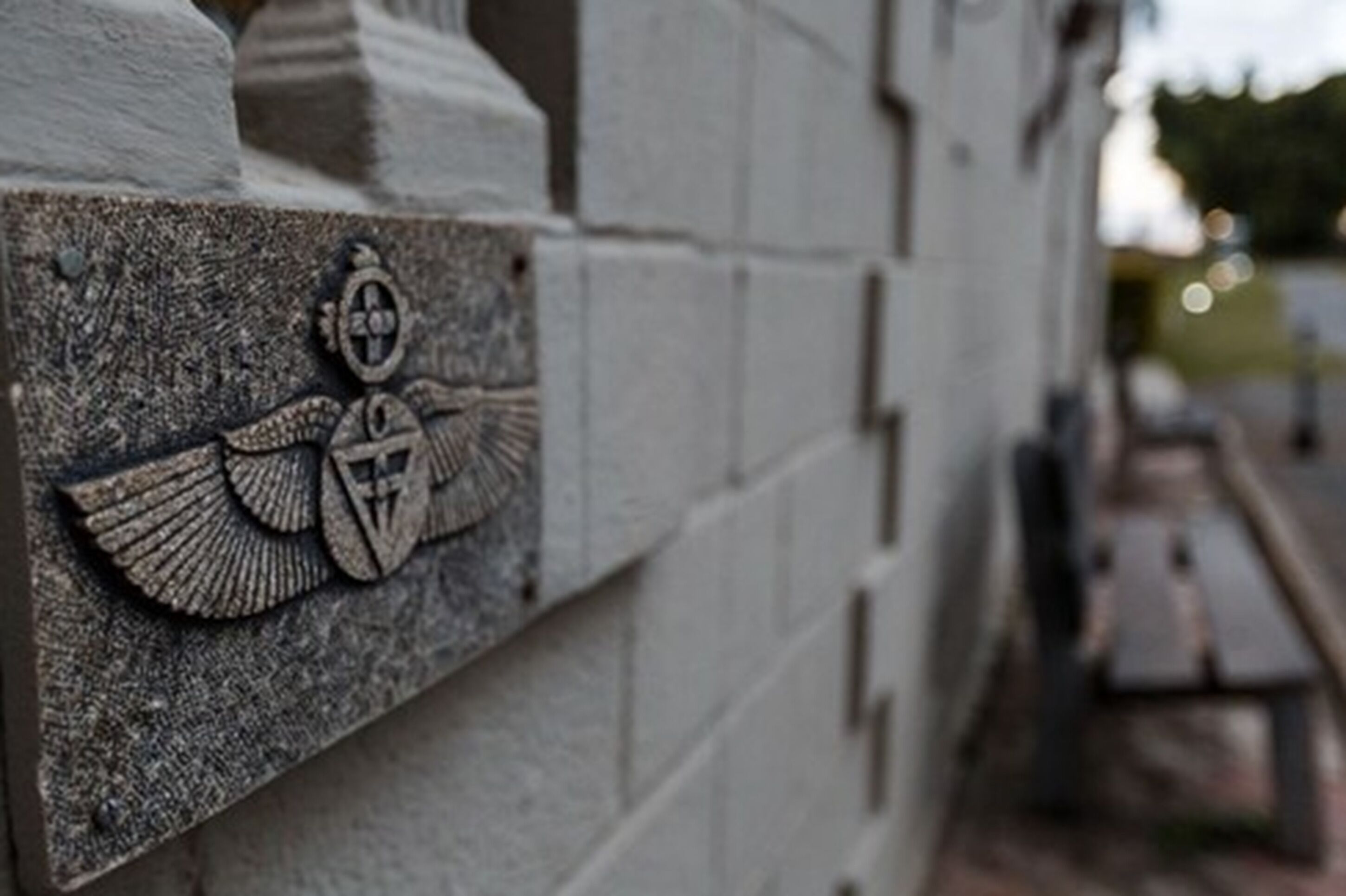 A stone wall with a carved emblem featuring a shield and wings.