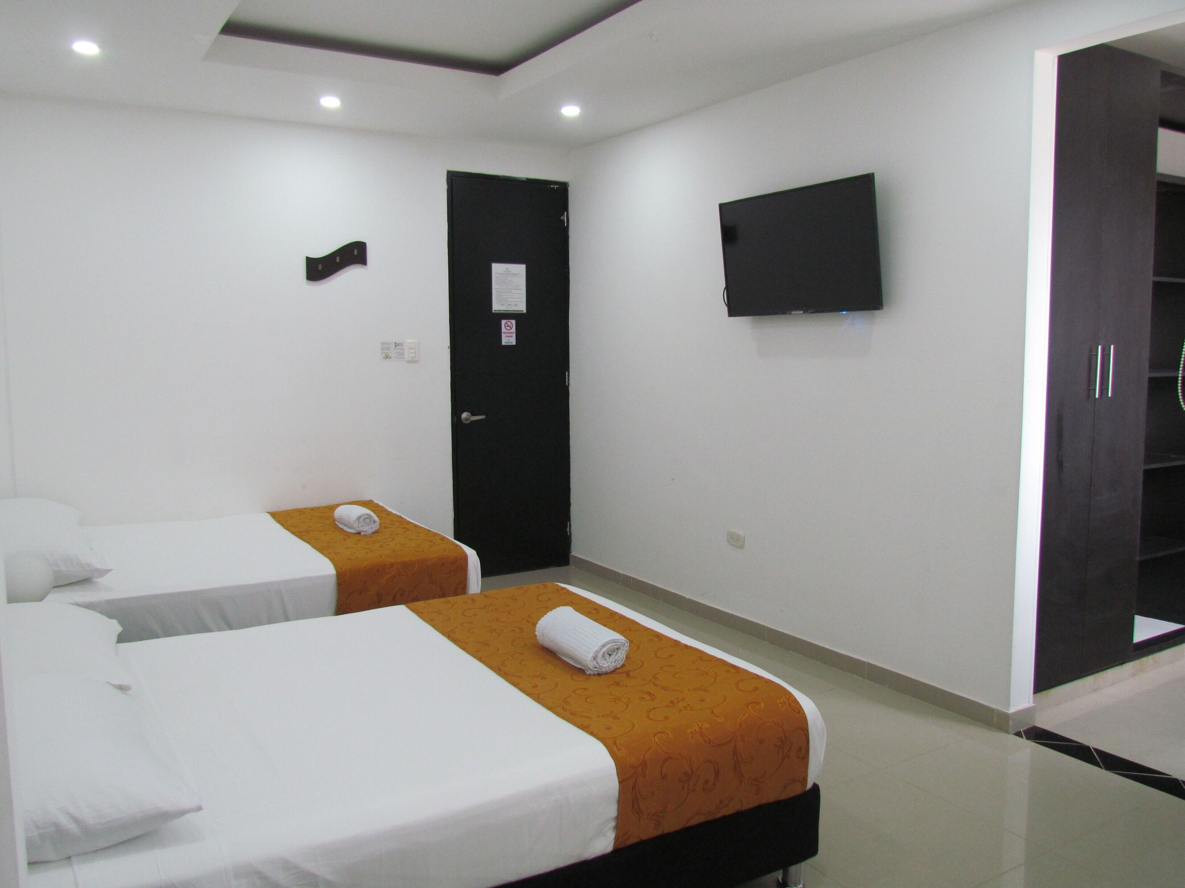 A hotel room with two beds, a flat-screen TV, and a wardrobe.