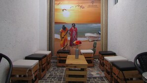 Un rincón al aire libre acogedor con bancos de madera y una mesa, enmarcado por un mural de una playa.