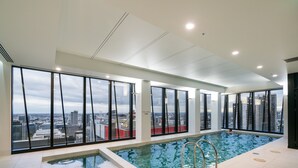 A modern indoor pool with large windows offering city views. - StayIcon Serviced Apartment On Collins (Melbourne)