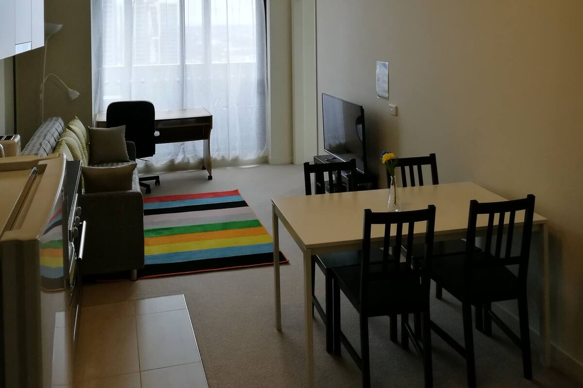 A living room with a sofa, TV, and a dining area with chairs and a table.