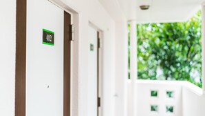 Un couloir d’hôtel avec une porte portant le numéro « 402 » et donnant sur un paysage verdoyant.