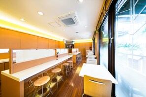 Een modern restaurant met houten vloeren, witte barstoelen en een lange toonbank.