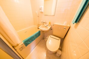 Een compacte badkamer met een bad, wastafel, toilet en een spiegel.
