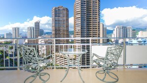 A balcony with two chairs and a small table, overlooking a cityscape with tall buildings. - Marina Hawaii Vacations at the Ilikai Tower (Honolulu)