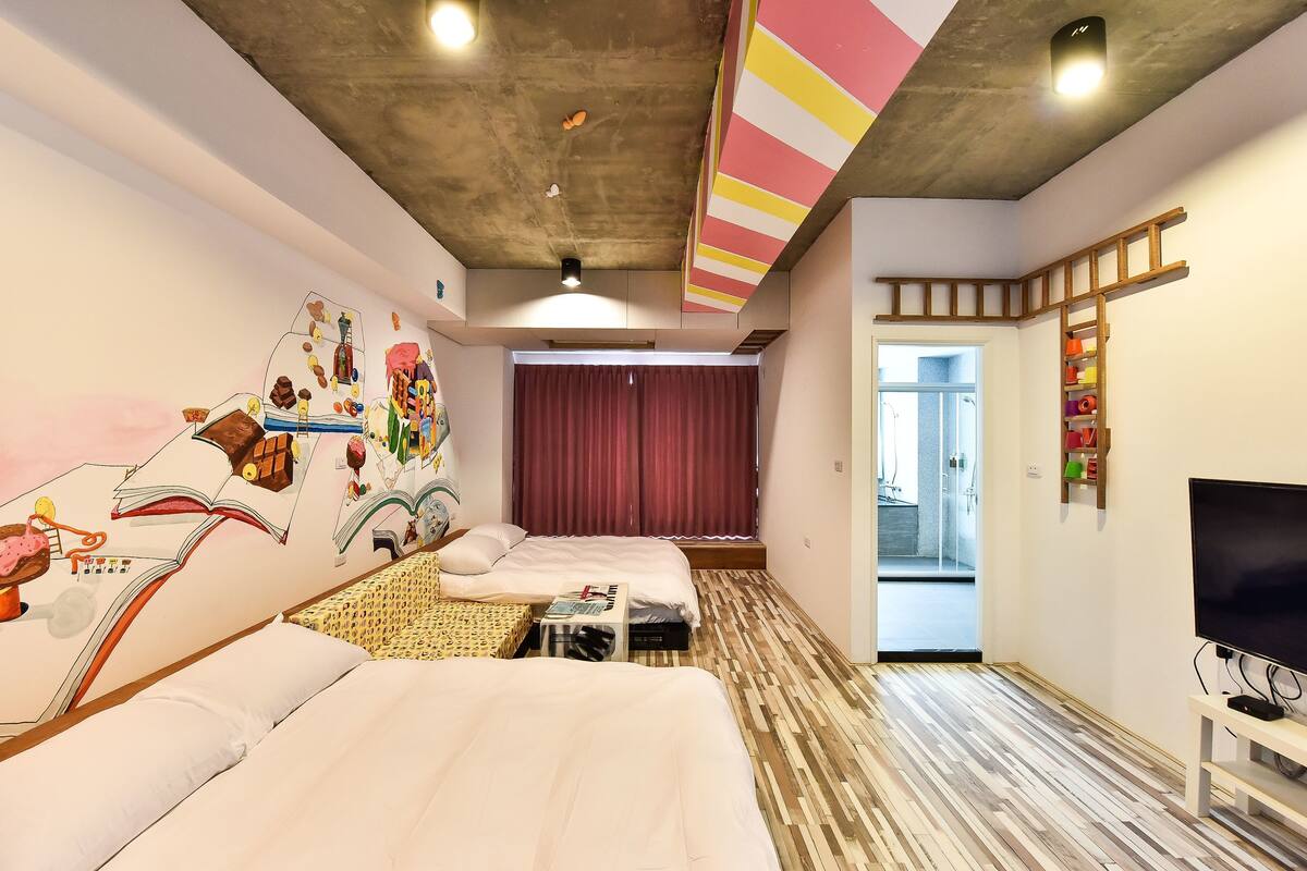 A hotel room with two beds, a TV, and a mural on the wall.