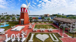 Un moulin à vent, un espace extérieur aménagé avec des sièges et une pelouse en forme de cœur sur laquelle est inscrit « LOVE I ♥ U ».