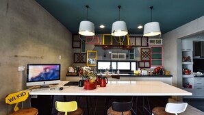 Une cuisine moderne dotée d’un îlot central, de tabourets de bar et de luminaires suspendus.