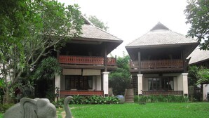 A building with a traditional architectural style, featuring a two-story structure with a balcony on the upper floor. - Pai River Corner Resort (Pai)