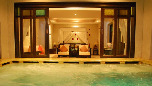 A spa area with a hot tub, a sofa, and a small table with a lamp. - Pai River Corner Resort (Pai)