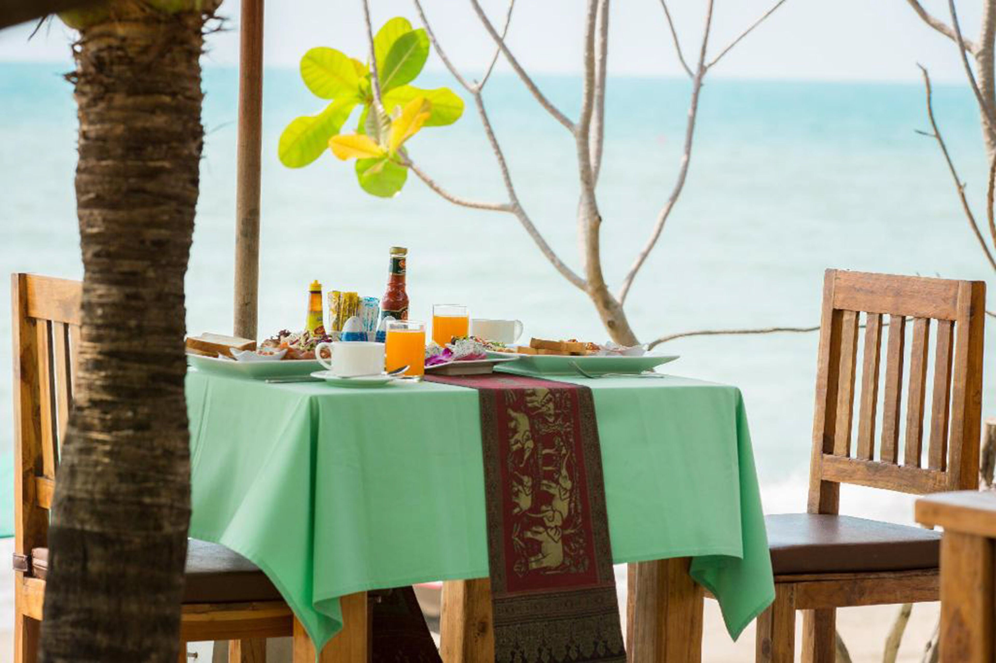Una mesa dispuesta con alimentos para el desayuno y vista al océano.