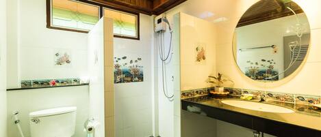 Een badkamer met toilet, douche, wastafel en een spiegel.