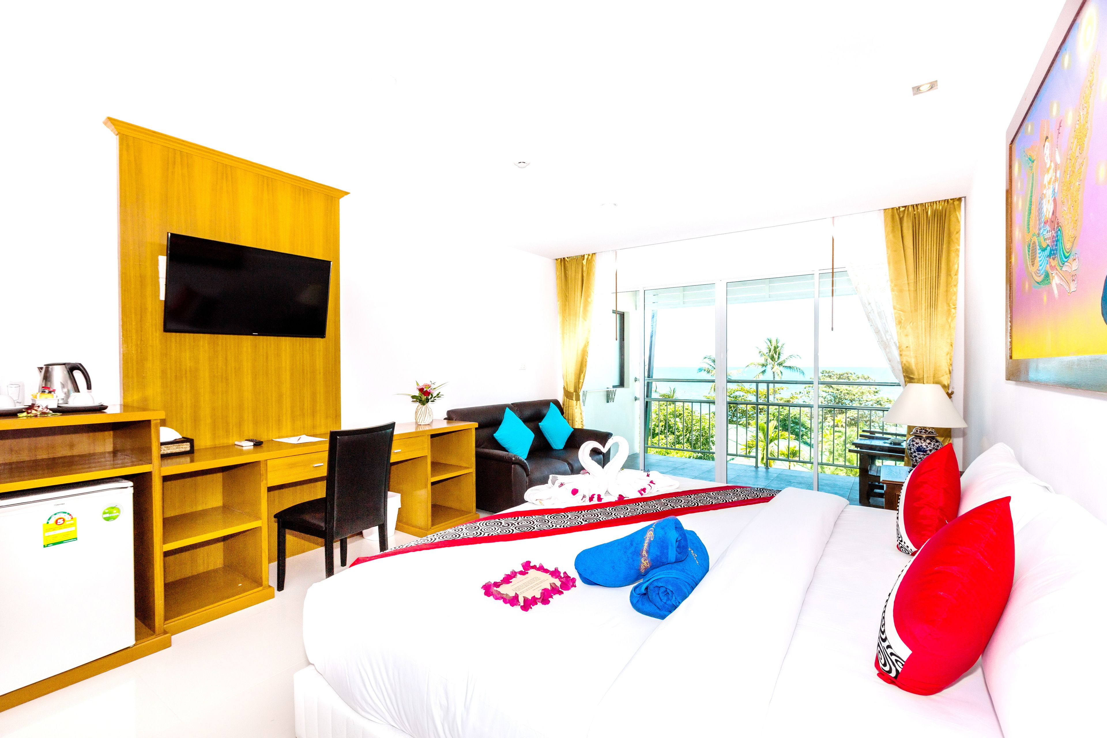 A hotel room with a bed, a desk, a chair, a TV, and a balcony with a view.