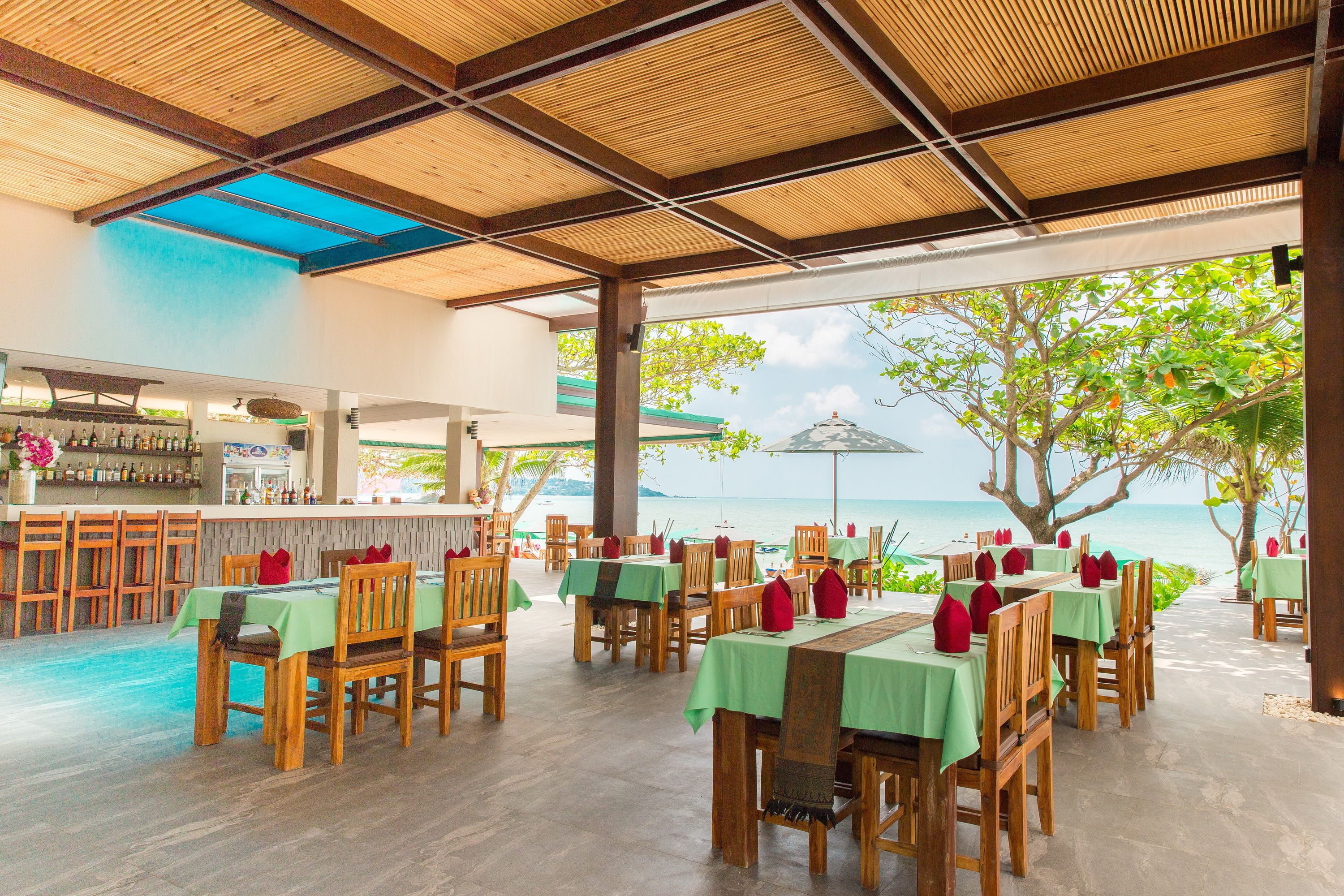 A restaurant with outdoor seating overlooking a pool and the sea.