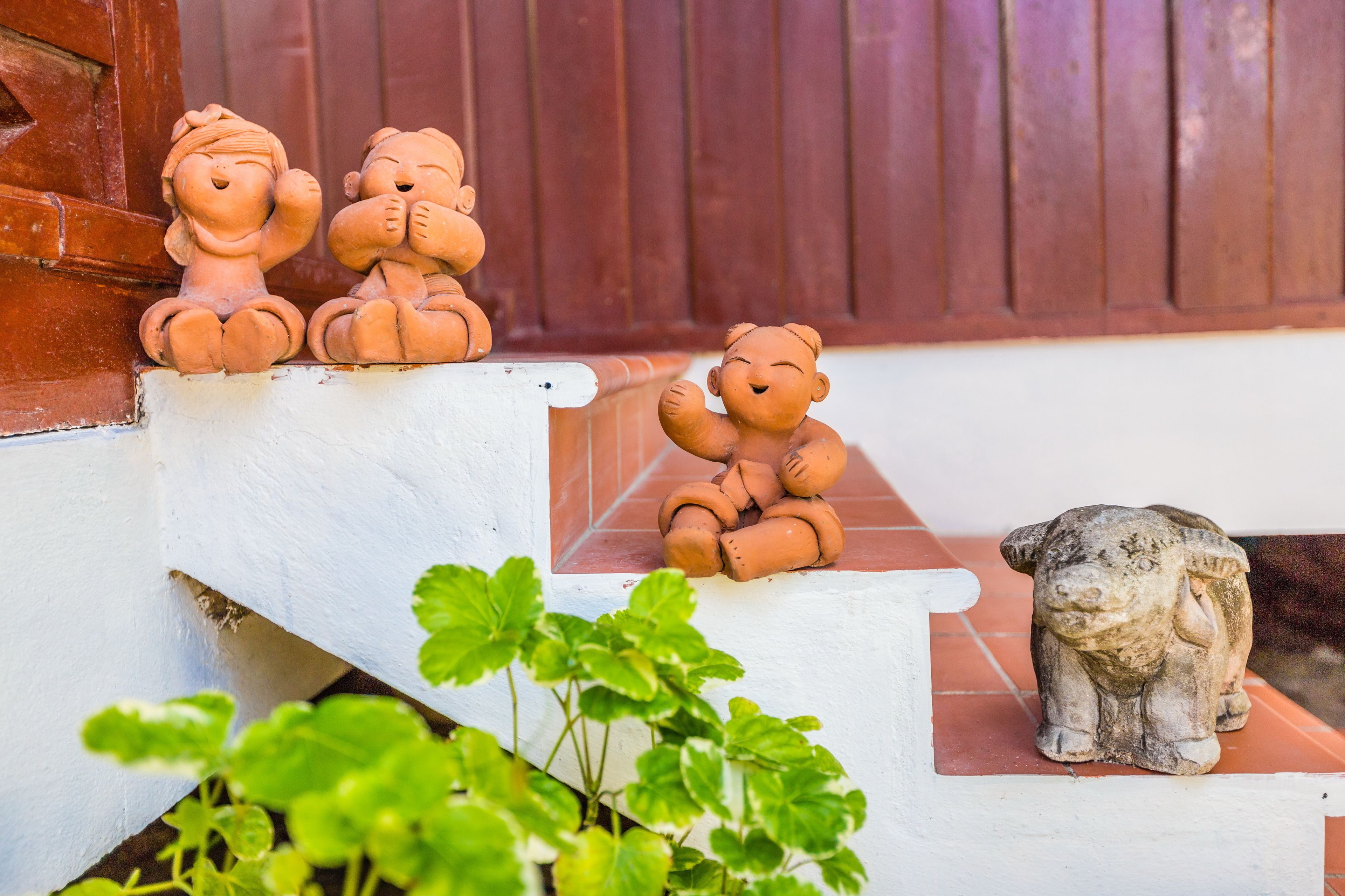 Petites figurines d’animaux en terre cuite sur un escalier blanc.