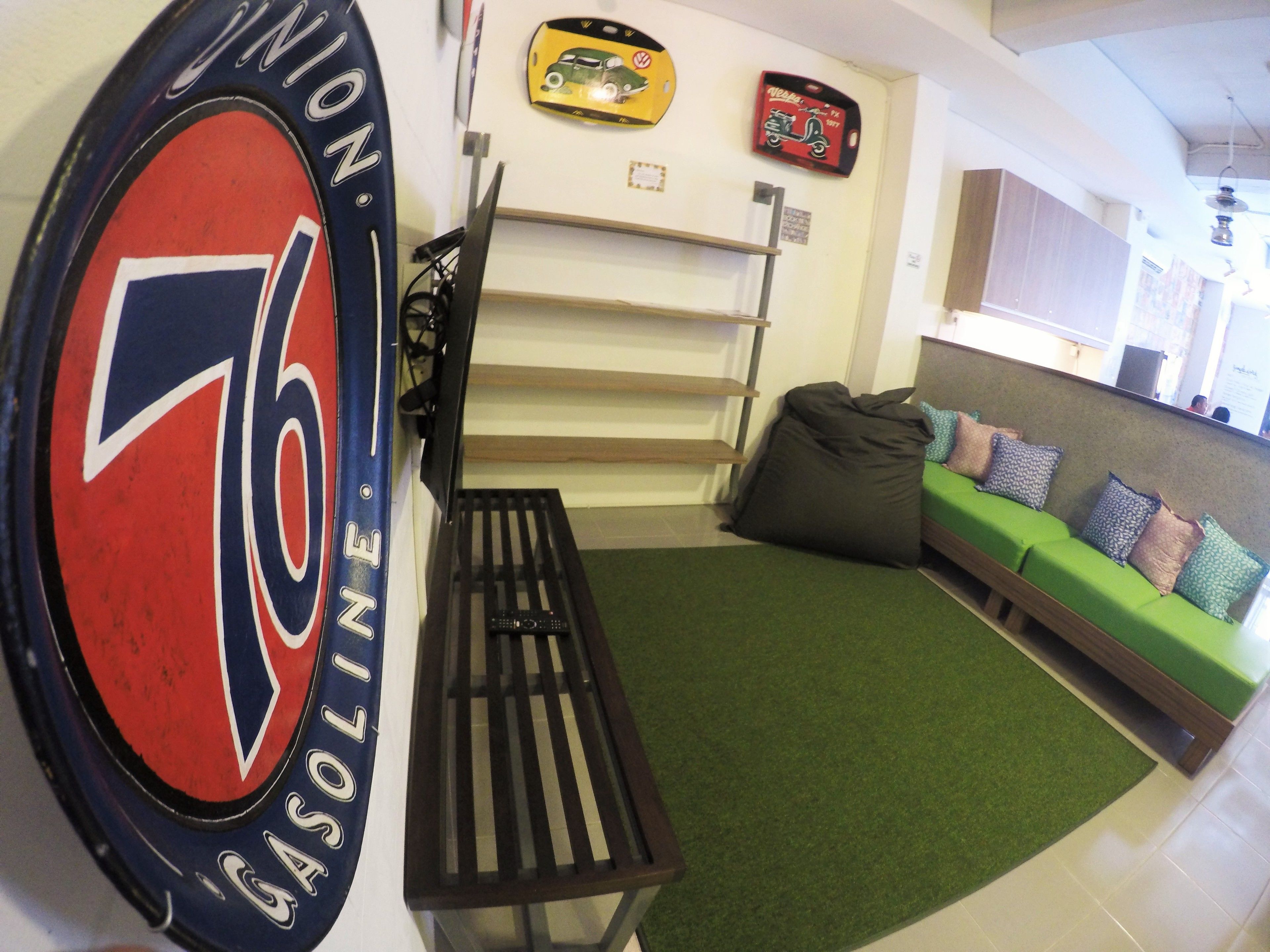 A room with a large wall clock, a green sofa, a bench, and a wall-mounted shelf.