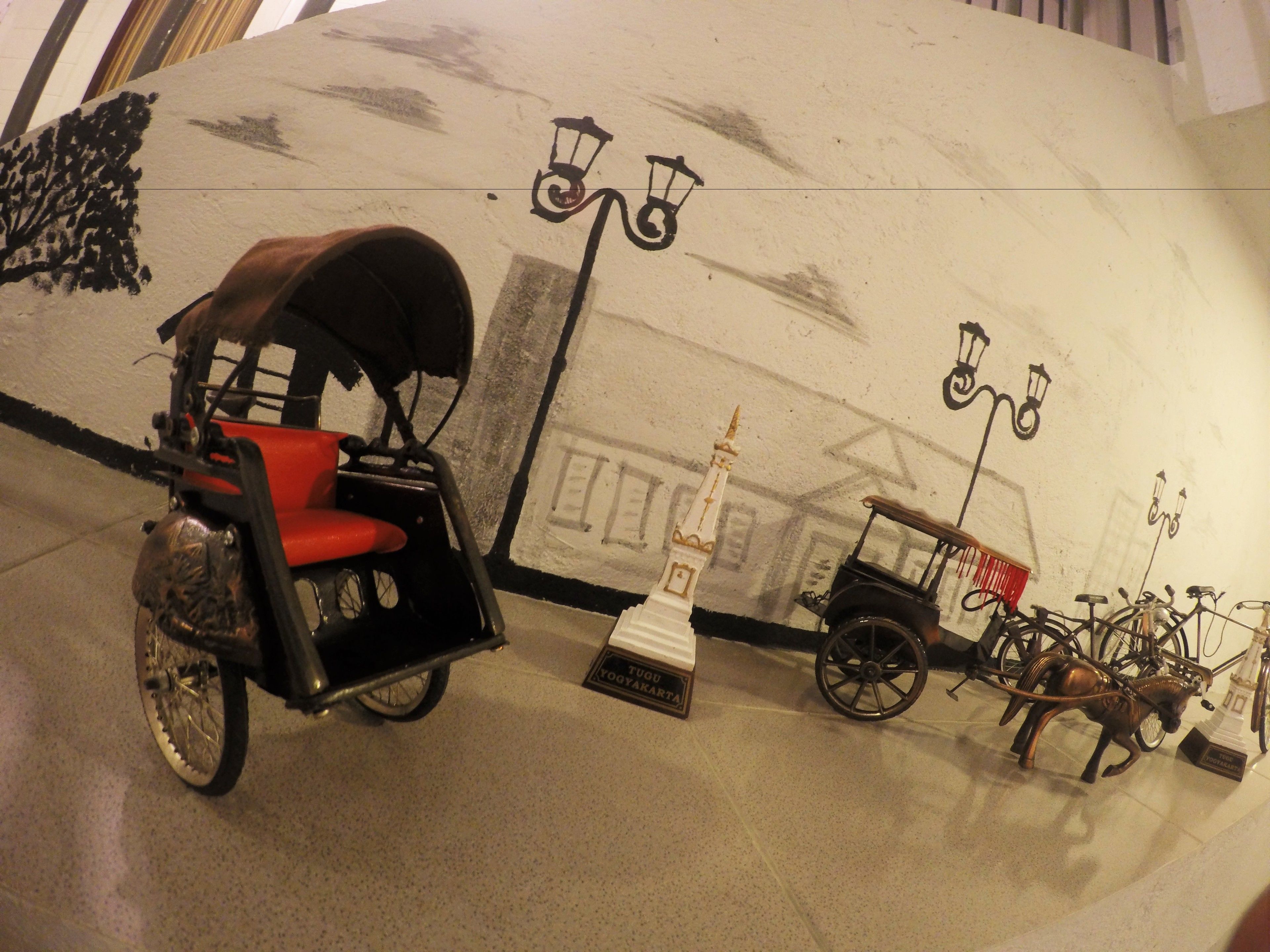 A museum exhibit with a horse-drawn carriage, a vintage car, and bicycles.