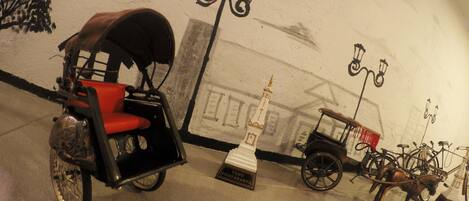 A museum exhibit with a horse-drawn carriage, a vintage car, and bicycles.