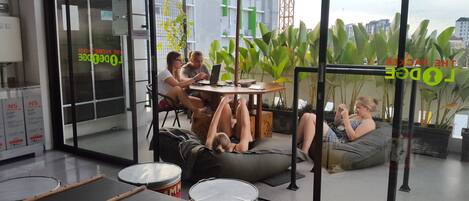 A modern office space with a glass partition, a round table with a laptop, and a person lying on a bean bag chair.