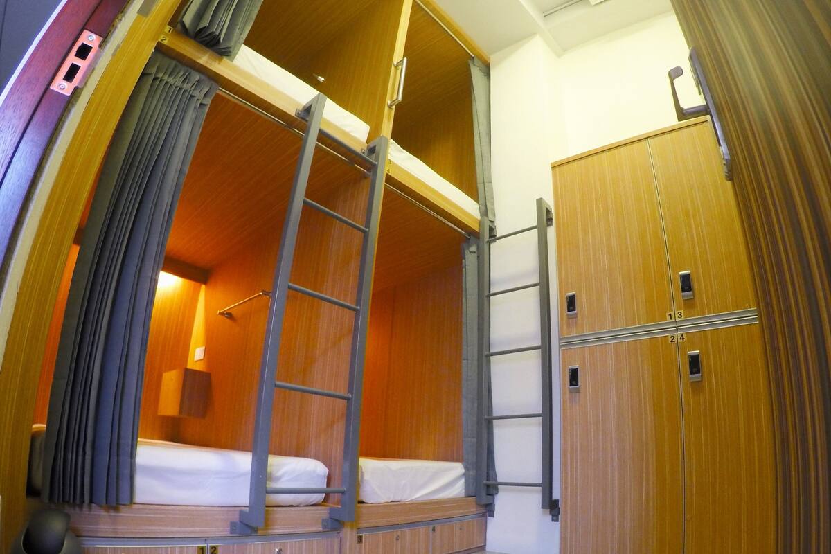 Pieni huone, jossa on kerrossänky, vaatekaappi ja tikkaat.