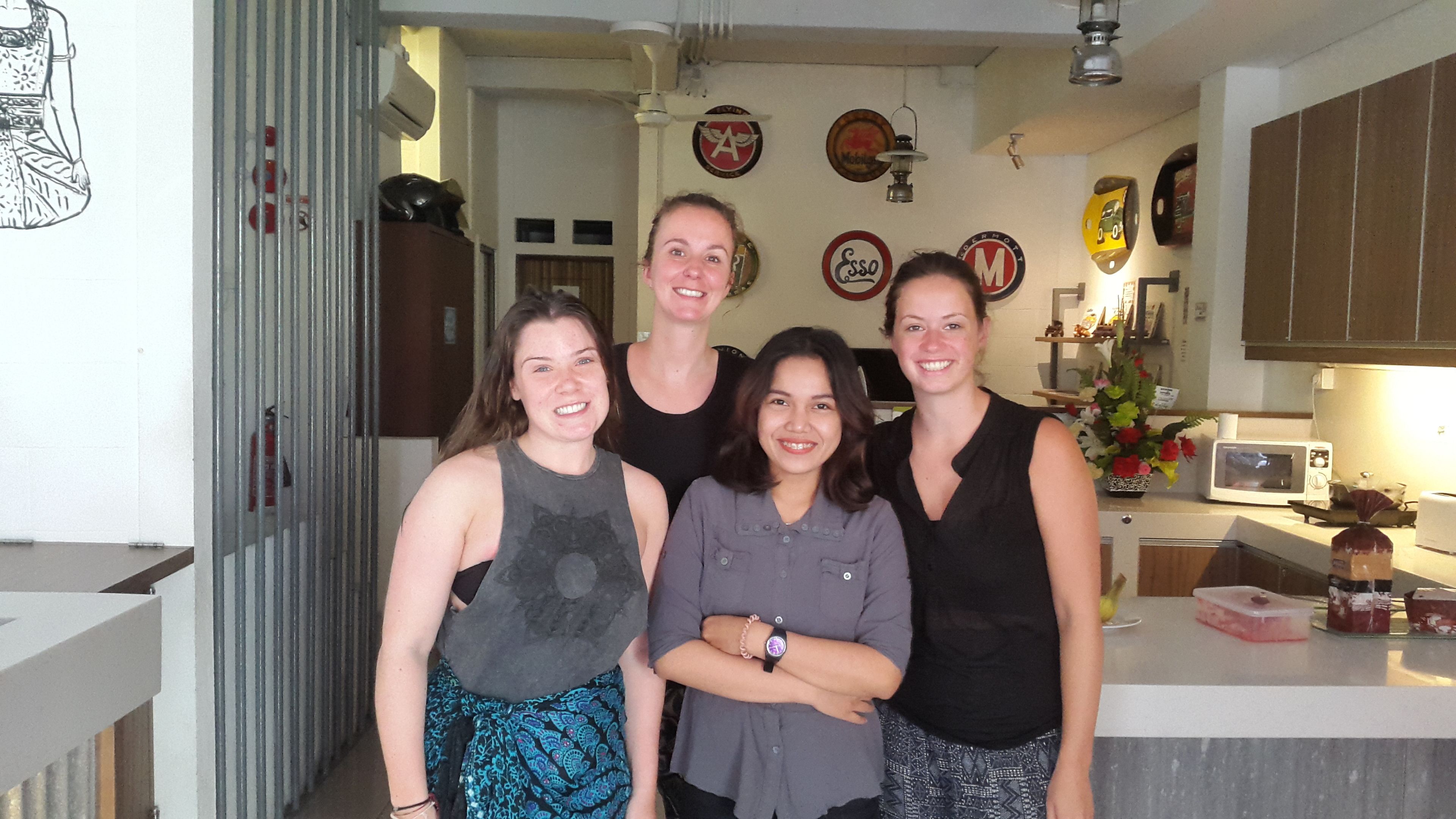A group of four people standing in a kitchen with various decorative plates on the wall.