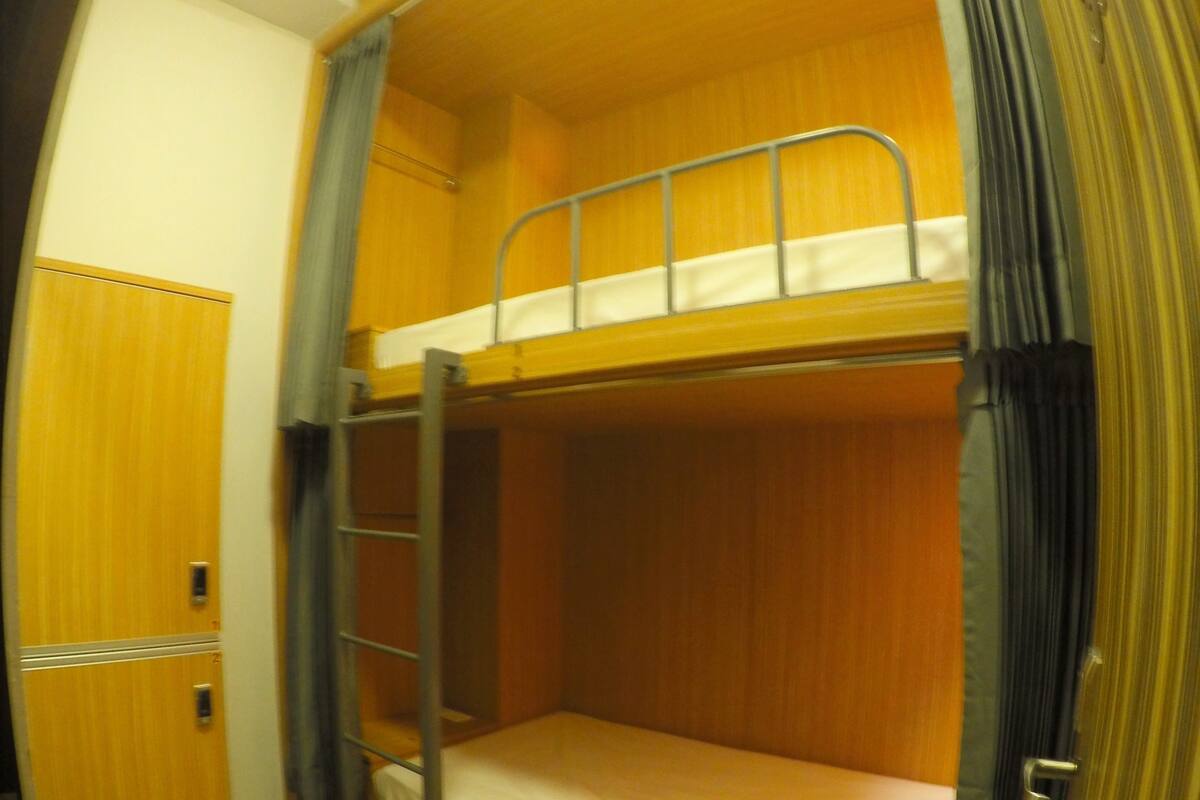 Huoneessa on kerrossänky, joka on valmistettu puusta, siihen kuuluu tikkaat ja siinä on myös vaatekaappi.