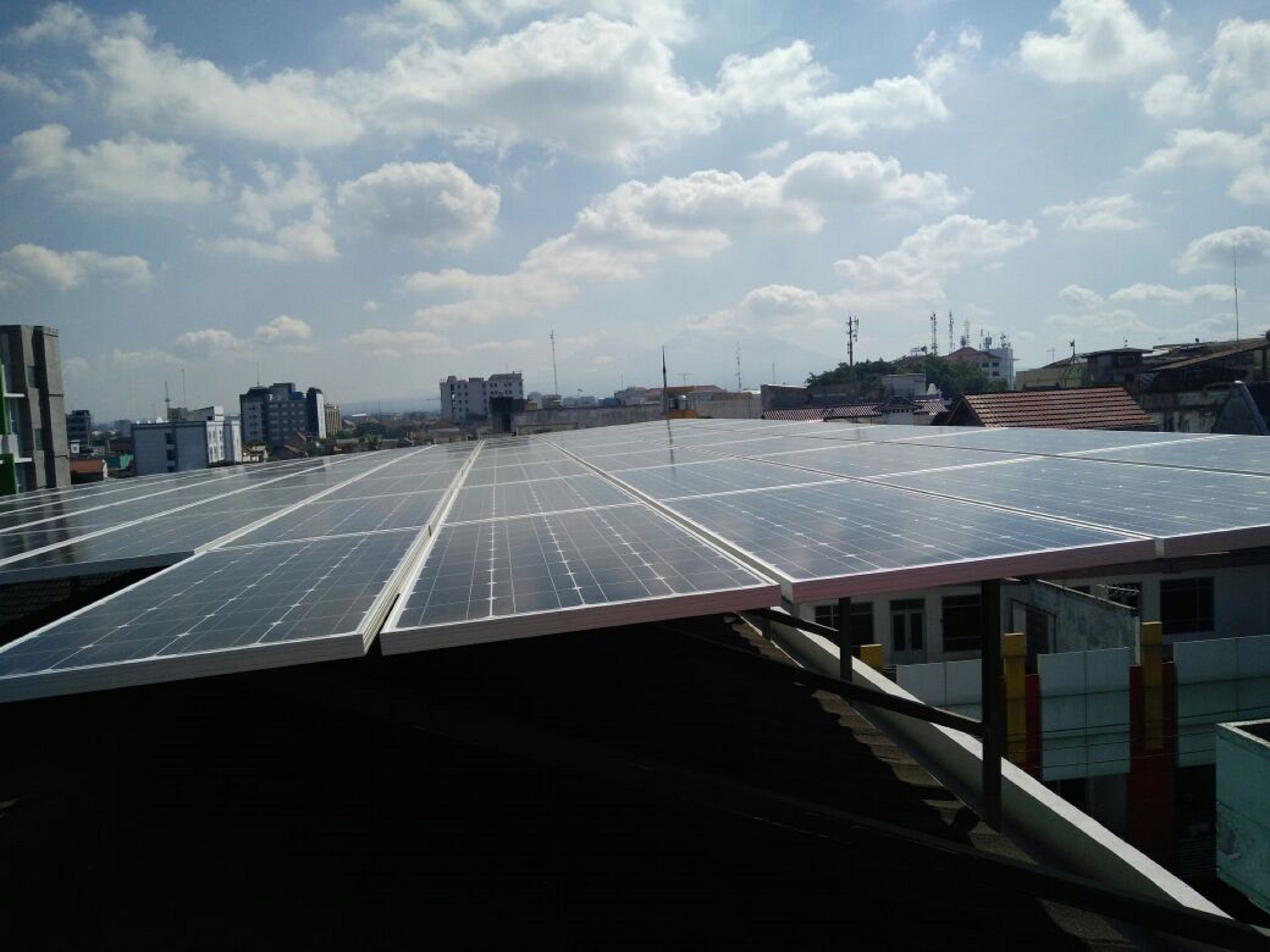 Una azotea con paneles solares bajo un cielo parcialmente nublado.