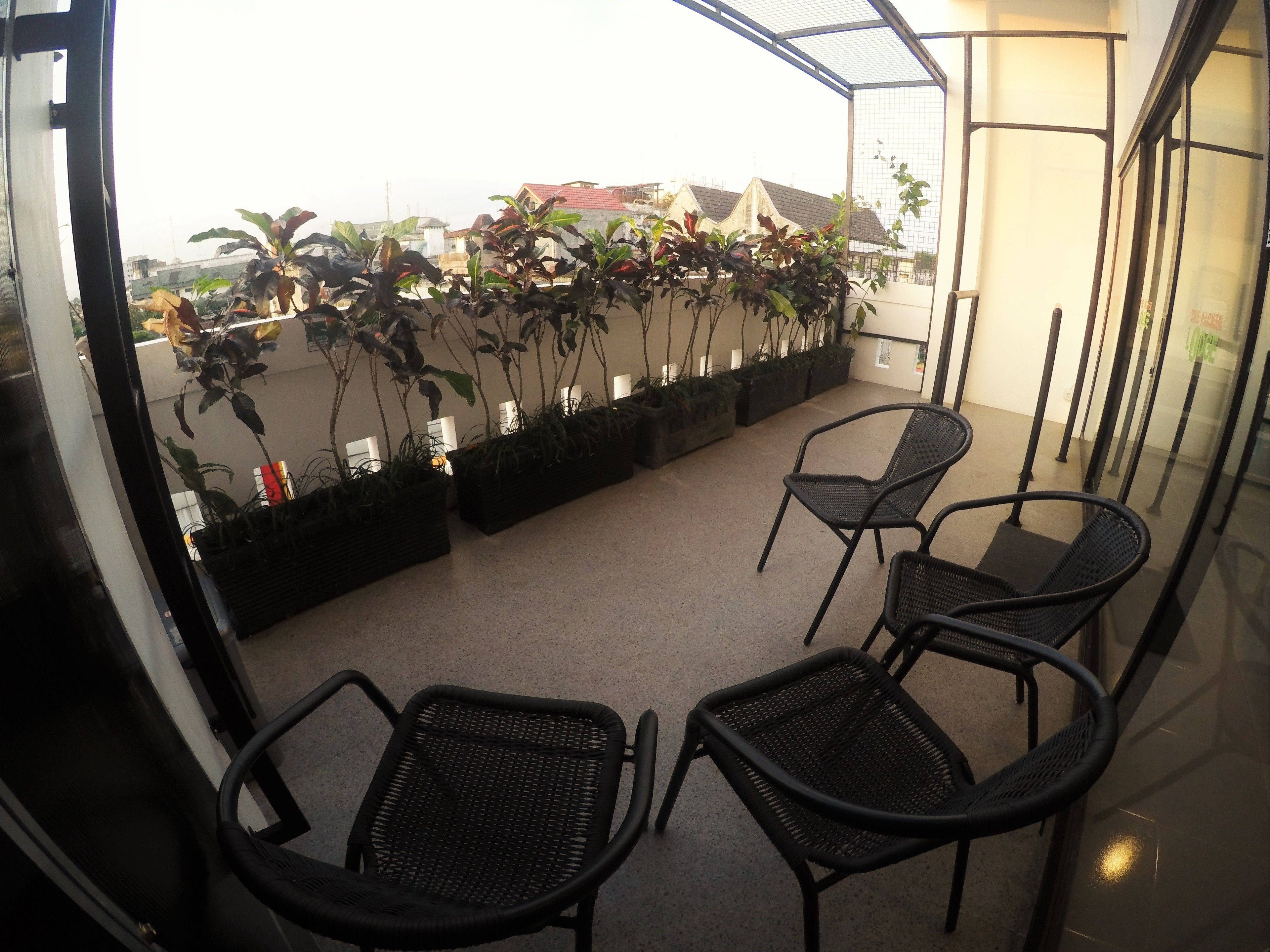 A balcony with potted plants and black chairs.