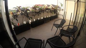 A balcony with potted plants and black chairs.
