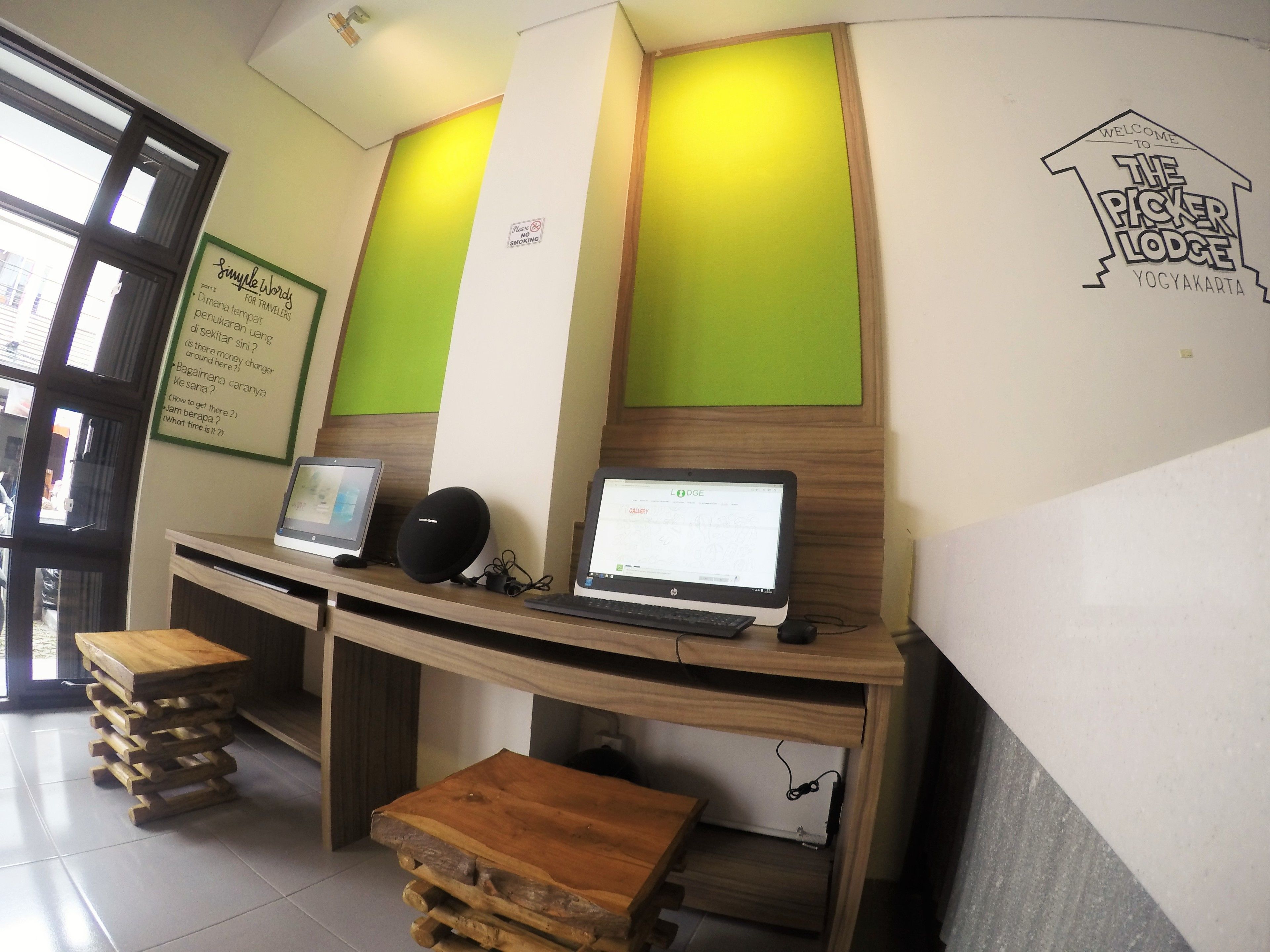 A reception desk with two laptops, a speaker, and a sign indicating no smoking.
