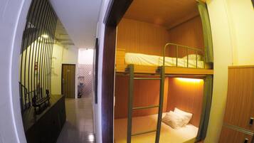 A bunk bed room with a wooden bunk and a lower bunk, a small desk, and a chair.