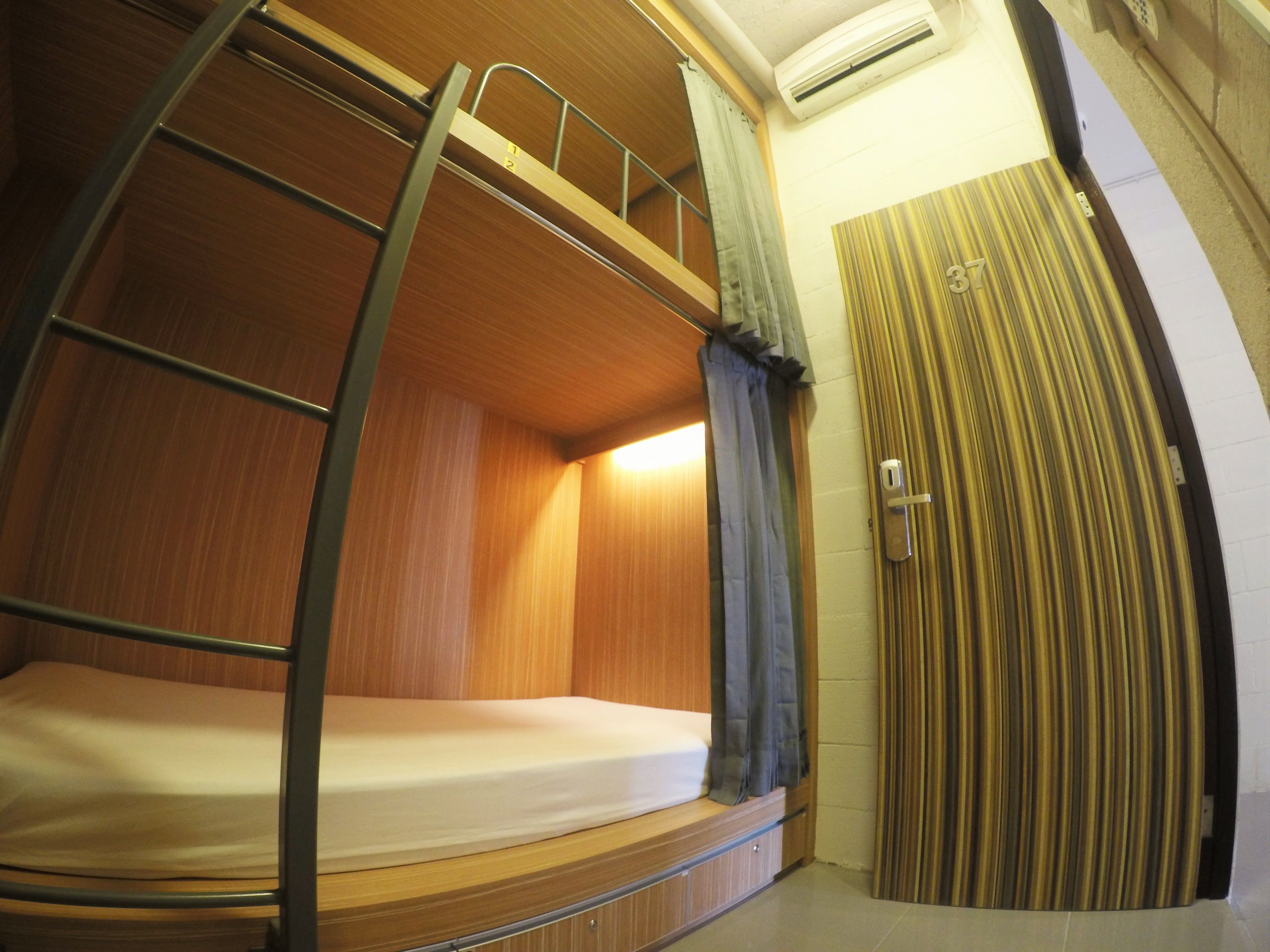 A bunk bed room with a ladder, a curtain, and a door.