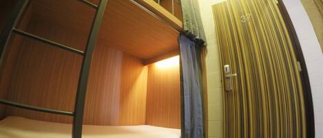 A bunk bed room with a ladder, a curtain, and a door.